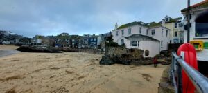 A view across the beach to houses built on rocks of St Ives in Cornwall..