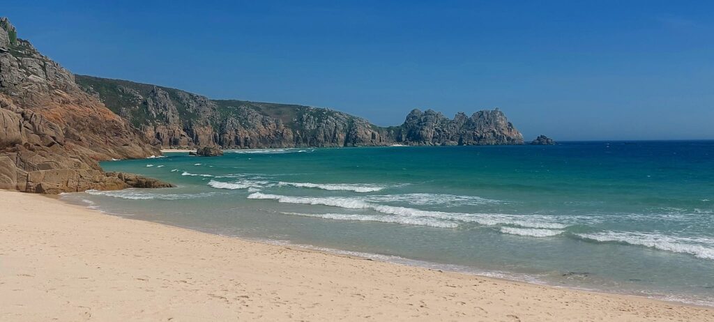 deserted sandy beach with rocky headland and deep blue sea and sky