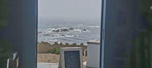 view over rocks in the grey sea through doorway with a signboard in the foreground